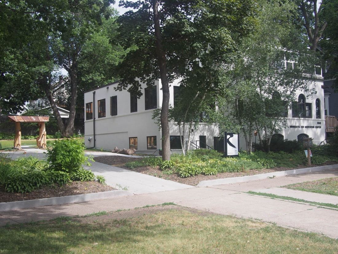 The Minnesota Zen Meditation Center, a white two-story building among trees, with a wooden gate at the left