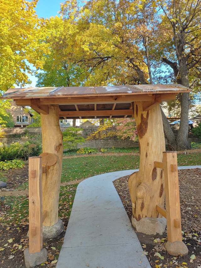 The center’s carved wooden gate in autumn, a path running through it under yellow leaves